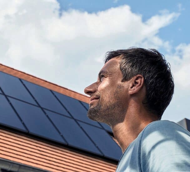 Muž pred strechou s fotovoltaickými panelmi