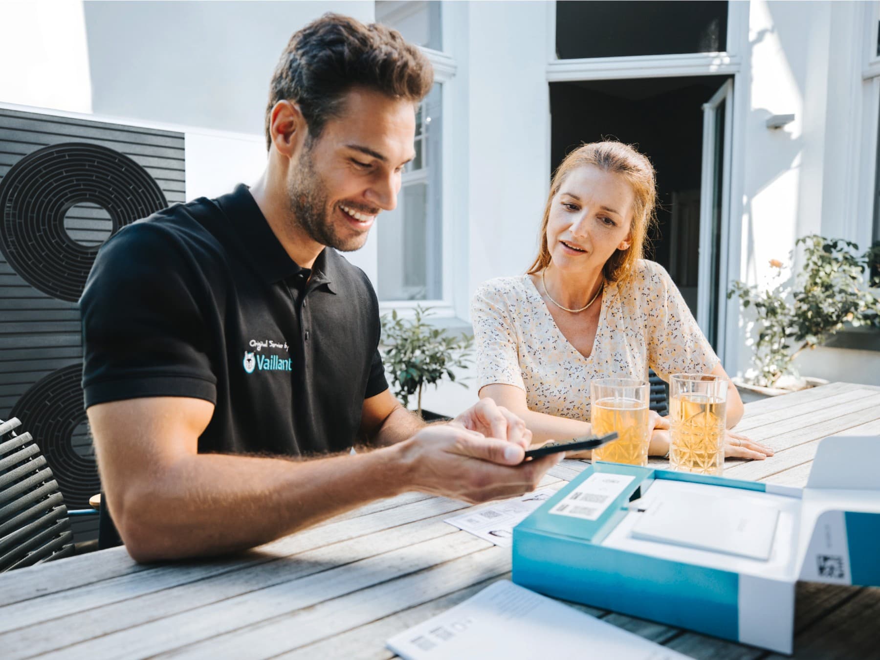 Servisný technik spoločnosti Vaillant so smartfónom a zákazníkom vedľa neho